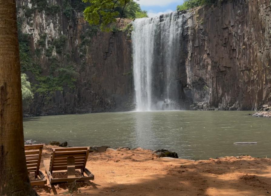 Cadeiras próximas à margem com vista para a cascata