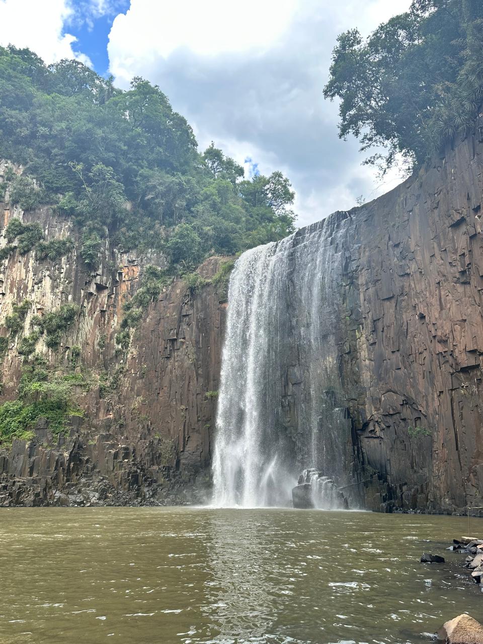 Cascata Vitória com queda d'água cercada por paredões de pedra e mata